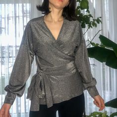 It's our shiny long sleeve v-neck blouse with envelope details. The color is polished silver or we can say metallic color. This blouse produces with made order. It will show the perfect look for every body size. It can be arranged neck decollete. After your order, we start to process. We will get ready to ship in approximately 3-5 days. It is limited to fabric stock. So, we won't promise to make this product when we stock out. You can always ask questions about your size or for any help. Fabric: Elegant V-neck Long Sleeve Top For Winter, Glamorous V-neck Winter Top, Elegant Long Sleeve Top For Fall Party, Silver V-neck Top For Fall, Chic Long Sleeve Wrap Top For Party, Chic Silver V-neck Top, Elegant Long Sleeve Top For Winter Party, Elegant Long Sleeve Party Top For Winter, Chic Long Sleeve Tops With Sheen