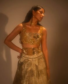 Step into refined elegance with the goldusion ensemble, where traditional craftsmanship meets modern innovation. The metallic lehenga, crafted from hand-crushed gold fabric, exudes opulence, while the detachable corset belt and blouse are fully embellished for added glamour. Architectural embroidery, inspired by mughal lattice motifs, adds a striking, textured dimension. A masterful fusion of texture, form, and cultural heritage, this ensemble redefines contemporary sophistication. Metallic Lehenga, Architectural Embroidery, Lehenga And Blouse, Corset Belt, Gold Fabric, Cultural Heritage, Photographic Lighting, Traditional Techniques, Lattice