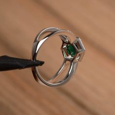 It is a lab emerald ring. The main stone is 7mm*7mm round cut, weight about 1.3 carats. The basic metal is sterling silver and plated with rhodium. To change the metal to a solid gold (white/rose) or platinum is also available, please ask for a quotation if you want. You can also go to my shop Home for more elegant rings: https://www.etsy.com/shop/godjewelry?ref=hdr_shop_menu More lab emerald rings: https://www.etsy.com/shop/godjewelry?ref=seller-platform-mcnav&section_id=20709240 Customizat Green Emerald Ring In Sterling Silver With Halo Setting, Silver Solitaire Emerald Rings, Emerald Ring In Sterling Silver With Round Band, White Gold Emerald-cut Cubic Zirconia Ring, White Gold Emerald Cut Cubic Zirconia Ring, Fine Jewelry With Halo Setting For May Birthstone, May Birthstone Jewelry With Halo Setting, Fine Jewelry Emerald Ring With Bezel Setting, Round Cut, Fine Jewelry Emerald Ring With Bezel Setting