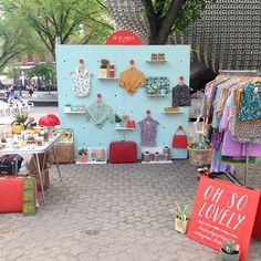 an outdoor market with clothes and other items on display