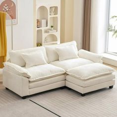 a living room with a large white sectional couch and yellow drapes on the windowsill