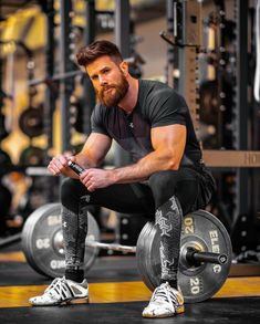 a man squatting on a barbell in the gym