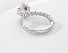 a close up of a ring with a flower on the side and a diamond in the middle