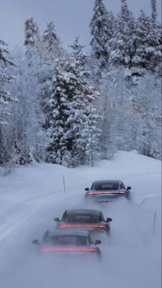 three cars driving down a snowy road with trees in the background and snow on the ground