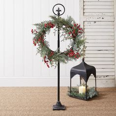 a candle holder with a wreath on it next to a lantern