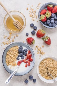 two bowls of cereal, yogurt and strawberries with honey on the side