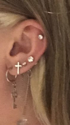 a close up of a person with ear piercings and cross on the back of their ear