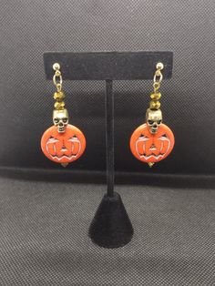 Our creative, handcrafted jewelry is hand made by a woman owned and operated small business with a passion for unique jewelry. We have tons of unique pieces that will make your outfit pop, or let your personality shine. Trick or treat! these lovely dangles are ready for a night out on Halloween, or anytime you want to add a bit of spooky to your outfit. With Jack o lanterns swinging on the ends, and golden skulls joined by sparkling golden glass beads, they are sure to catch the eye, and cause smiles everywhere you go. These handcrafted earrings are 25mm wide by 58mm long from the stud to bottom of earrings. The studs have 10mm posts. Disclaimer: I do my best to represent my handmade products as accurately as possible. However, due to lighting sources and display settings, colors may be sl Themed Gold Earrings For Gifts, Vintage Beaded Earrings As Gift, Unique Adjustable Earrings For Party, Vintage Adjustable Beaded Earrings For Gift, Czech Glass Jewelry With Matching Earrings For Gifts, Unique Czech Glass Jewelry As A Gift, Czech Glass Round Jewelry Gift, Czech Glass Jewelry Set With Matching Earrings As Gift, Halloween Dangle Jewelry With Matching Earrings