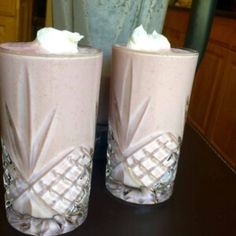 two glasses with whipped cream in them sitting on a table