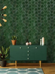 a green cabinet with plants and candles on it in front of a patterned wallpaper