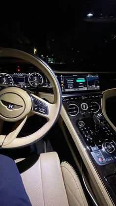 the interior of a car with steering wheel, dashboard and dash lights on at night