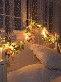 a bed with lights on the headboard and flowers hanging from it's sides