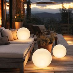 three lights on the ground next to a couch and table with an umbrella in the background