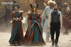 the actors are dressed in costumes and standing on a dirt ground with other people behind them