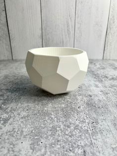 a white ceramic bowl sitting on top of a wooden table next to a wood wall