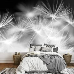 a bed sitting under a large wall mural with dandelions in the air on it