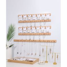 a collection of necklaces and earrings hanging on wooden shelves next to a potted plant