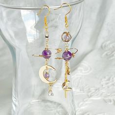 Amethyst Planet and Moon Earrings Made from the beautiful gemstone amethyst, these earrings make the perfect gift for those born in February. Boasting a delicate planet design accompanied by a luminous moon and star drop, these earrings are both versatile and eye-catching. As a gift shop, we offer a complimentary gift box for every order. Detail: Length of one earring - 75mm; size of beads - 5-8mm Material: ear wire - sterling silver; beads - natural Amethyst, Pietersite stones;  Note: the Amethyst Planet and Moon Earrings are handmade locally in the UK, each pieces would vary slightly in detail.  About postage: Standard postage When choosing standard postage, we assume this order is for yourself, or you will wrap the item yourself before giving it out as a gift (the complimentary gift box Celestial Round Crystal Earrings As Gift, Celestial Round Crystal Earrings For Gift, Purple Pierced Crystal Earrings As Gift, Handmade Purple Celestial Earrings, Celestial Amethyst Gold Jewelry, Purple Celestial Dangle Earrings, Celestial Purple Dangle Earrings, Celestial Crystal Pierced Earrings For Gift, Celestial Amethyst Jewelry Gift