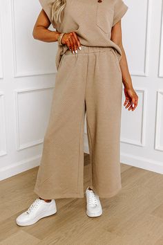 - These casual-chic pants are a must-have! Their stylish design and relaxed fit make it perfect for elevating your everyday wardrobe. Achieve a luxe look with this fabulous piece! - Unlined material with a trendy texture - An elastic waistband - Functional side pockets - A wide legged silhouette that ends in straight hemlines Fall Wide Leg Khaki Pants With Elastic Waistband, Khaki Wide Leg Pants With Elastic Waistband For Fall, Comfortable Brown Fall Pants, Chic Wide-leg Sweatpants For Fall, Khaki Bottoms For Loungewear, Beige Sweatpants For Fall Loungewear, Beige Sweatpants For Loungewear In Fall, Neutral Sweatpants For Fall Loungewear, Beige Sweatpants For Fall Workwear