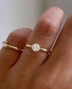 a woman's hand with two gold rings and a diamond ring on top of her finger