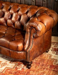 a brown leather couch sitting on top of a rug