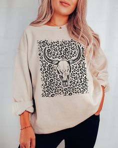 This stylish and unique Texas-inspired longhorn skull leopard print cowgirl sweatshirt will have you looking fashionable and ready for a rodeo in the desert. The boho western crewneck cow skull hoodie is perfect for any cowgirl who loves a good rodeo. ⭐️ * I T E M * I N F O* ✦ Gildan Unisex Sweatshirt ✦ This is made from a cozy, thinner material- perfect year round!  ✦ Printed using Direct To Garment style- Inks are printed directly into the fabric. ✦ Different sizing may effect placement of fin Casual Cow Print Tops For Fall, Casual Long Sleeve Tops With Cow Print, Casual Long Sleeve Cow Print Top, Western Crewneck, Austin Bachelorette, Leopard Print Sweatshirt, Longhorn Skull, Leopard Outfits, Diy Shirts