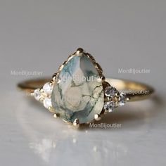 a gold ring with an aqua blue and white stone in the center, surrounded by diamonds