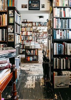 a room filled with lots of books on shelves next to a wooden floor and ceiling