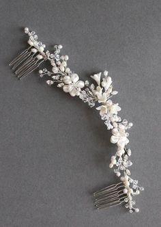 a bridal hair comb with flowers and pearls on the headpiece is laying on a gray surface