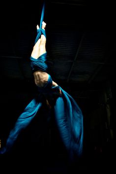 a woman is performing aerial acrobatic tricks in the dark