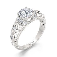 The beautiful engagement ring showcases a stunning round-cut stone center stone. Sparkling stones and intricate details create the ring's shank. On your wedding day, the coordinating stone and milgrain wedding band lends to the heirloom quality and completes this elegant ensemble.Carat Weight: 1.9 ctStone Size: 6.5 mmStone Type: Jeulia® StoneNumber of Stones: 1 Stone Color: Diamond WhiteStone Shape: RoundCarat Weight: 0.385 ctStone Size: 1,1.6,1.8,2 mmStone Type: Jeulia® StoneNumber of Stones: 2 Elegant Bridal Sets With Diamond Accents For Anniversary, Diamond Bridal Sets With Accent Stones For Promise, Classic White Diamond Ring With Accent Stones, Elegant Bridal Sets With Brilliant Cut, Formal Bridal Sets With Round Cut Accent Stones, Classic Wedding Diamond Ring With Round Band, Classic Round Band Wedding Rings, Wedding Diamond Ring With Cubic Zirconia Accent Stones, Refined Silver Ring With Center Stone