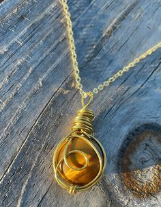 The natural, round tiger's eye cabochon crystal is hand-wrapped in gold wire with a looped, outer wrap design.  The pendant can also add either a gold or a silver chain to your order for a beautiful necklace!  Tiger's Eye is believed to bring balance and harmony, rid of fears, and provide courage with decisions to protect those who wear this crystal. Check out my Etsy shop for other Crystal Wrapped pendants! & IG: CrystalWrappedCreations - to see behind the scenes, and reserve items before poste Gold Cabochon Round Beads Jewelry, Adjustable Amber Wire Wrapped Jewelry, Gold Wire Wrapped Crystal Necklace For Gift, Yellow Gold Wire Wrapped Jewelry For Healing, Handmade Copper Wire Gold Necklace, Handmade Gold Copper Wire Necklace, Handmade Gold Necklace With Copper Wire, Gold Necklace With Hand Wrapped Round Beads, Gold Wire Wrapped Crystal Necklace With Round Pendant