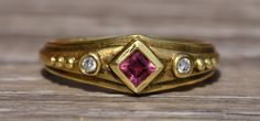 The Nashua: Etruscan Style Tourmaline Ring with Diamonds. The center is bezel set with a carre cut tourmaline with points at the directions of the compass. On either side of the center are bezel set round brilliant cut diamonds with three granulation's on either side. The ring is finished with a drop down to the edge and a sandblasted finish. Etruscan Jewelry, Vintage Gold Rings, Cute Engagement Rings, The Compass, Tourmaline Ring, Gems Jewelry, Custom Engagement Ring, Round Brilliant Cut Diamond, Cute Jewelry