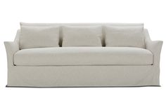 a white couch with four pillows on it's back and two arms, in front of