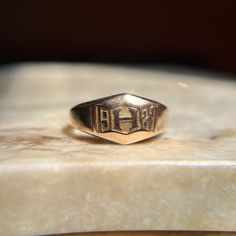 Beautiful vintage 1920's signet that was likely a class ring. This substantial ring features a letter H at the center, surrounded by the year of 1927 - nearly 100 whole years ago! The face shape is a cool geometric/trapezoidal design. Would make an awesome pinky ring if that is the finger it fits :) Wonderful vintage condition. A bit over 4.5 grams, this ring is heavy and well made for its size -- it has such a soothing presence on the finger! There is age appropriate wear and surface scratches Vintage Initial Ring For Anniversary, Vintage Stamped Initial Ring For Anniversary, Antique 14k Gold Signet Ring For Commemoration, Classic 14k Gold Stamped Signet Ring, Classic 14k Stamped Signet Ring For Commemoration, Classic Hallmarked Signet Ring For Commemoration, Vintage 14k Gold Rings For Commemoration, Classic Engraved Signet Ring For Commemoration, 14k Gold Heirloom Signet Ring For Commemoration