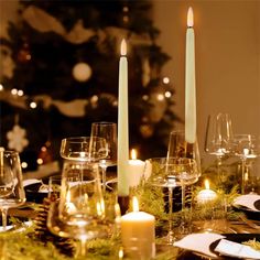 a table set with candles, plates and wine glasses for christmas dinner or holiday party