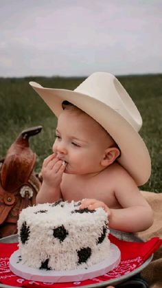 a baby wearing a cowboy hat eating a cake