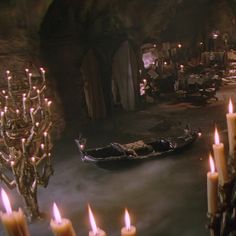 candles are lit in front of a boat inside a dark room with lots of other items