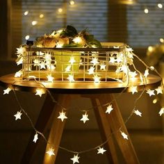 a table topped with a basket filled with fruits and vegetables covered in white star lights