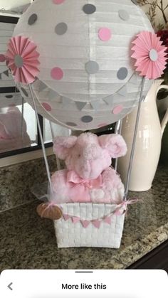 a teddy bear in a hot air balloon with pink and gray decorations on the top