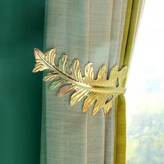 a curtain with a gold leaf decoration on the top and bottom of it, next to a green wall