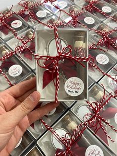 someone is holding a small box with some cookies in it and wrapped around red ribbon