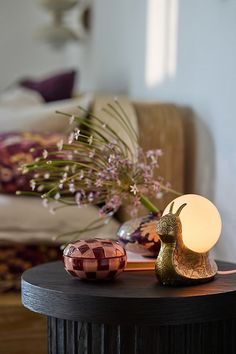 a table that has some flowers on top of it and a lamp in the middle