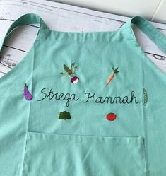 an apron with embroidered words and vegetables on the front that says, strega hamah