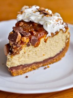 a piece of cheesecake on a white plate with whipped cream and chocolate toppings