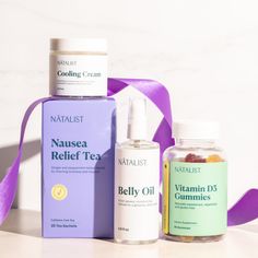 three bottles of vitamin oils and a bottle of gummies next to a purple ribbon