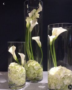 three clear vases with white flowers in them