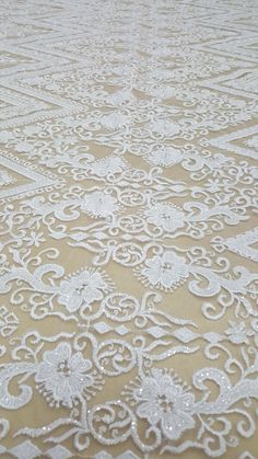 an image of a white lace with beads on it's edges and the background is beige