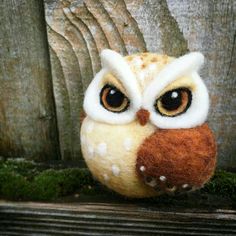 an owl stuffed animal sitting on top of a wooden table next to a fence with moss