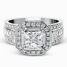 an engagement ring with a princess cut diamond surrounded by pave set diamonds on the sides